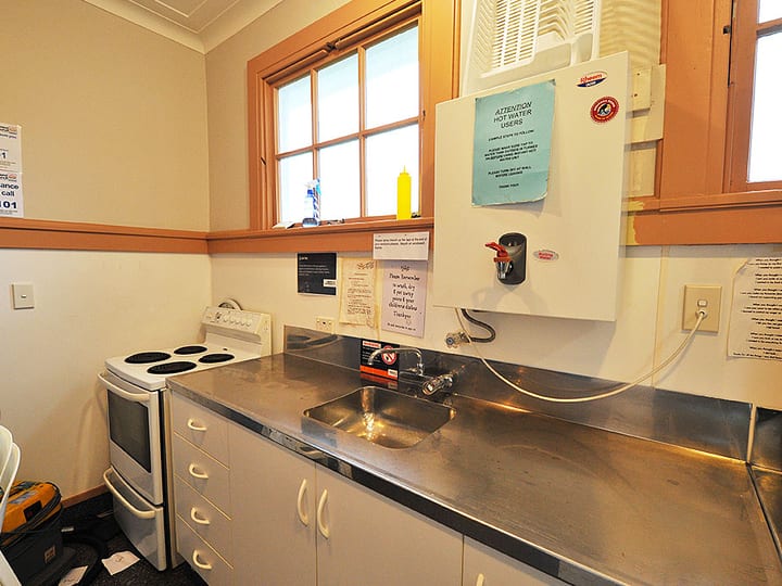 Small kitchen with stainless bench, sink, electric stove, and single window