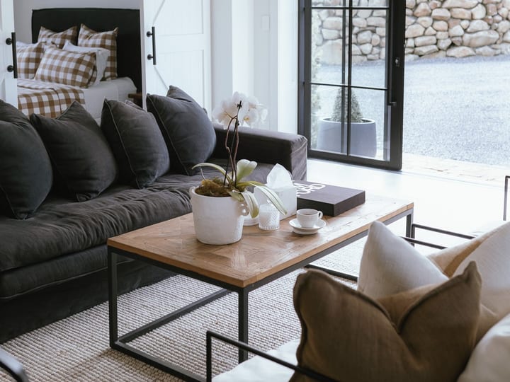 White interior sitting room with sliding barn door, dark sofa, and French doors to stone wall garden