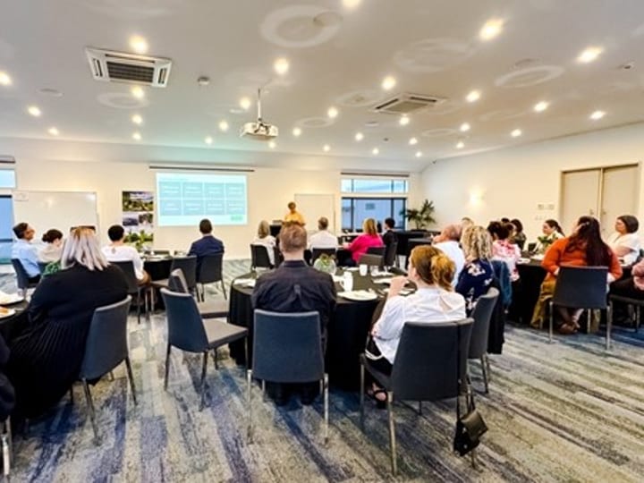Conference room set theatre-style with round tables and presentation screen