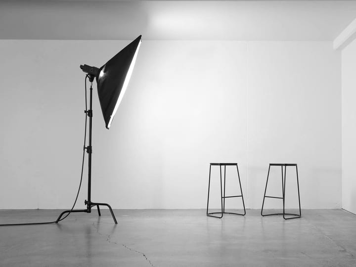 Studio space with softbox light, two metal stools, and white walls
