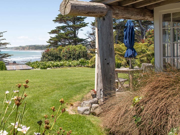 Villa verandah with rustic timber post gate, garden, and ocean view beyond