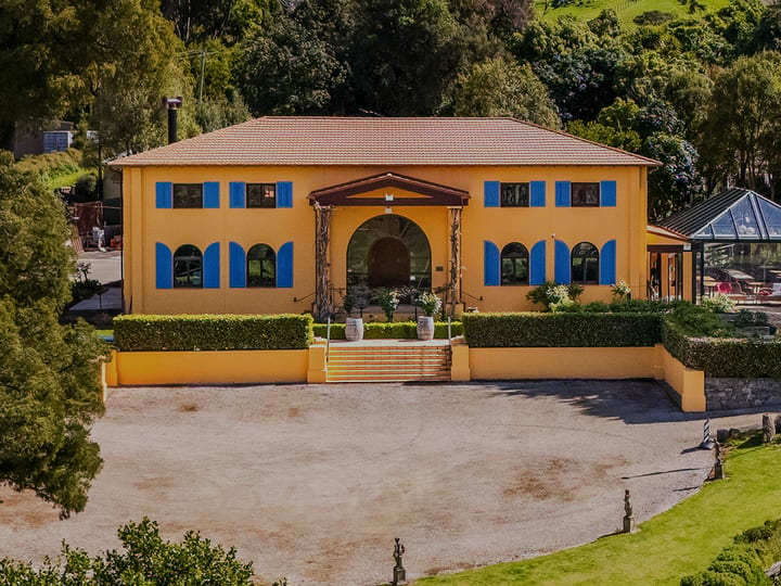 Aerial view of ochre winery building surrounded by trees and green hillside