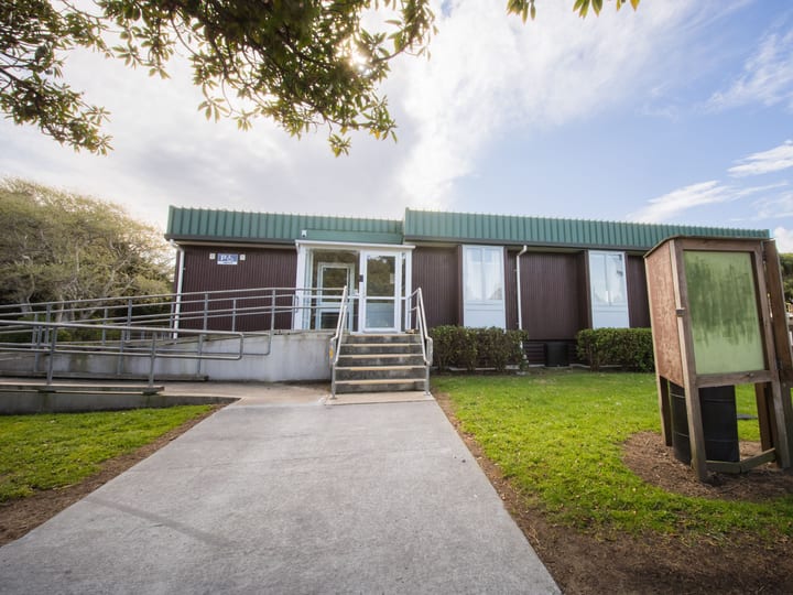 Single-storey community hall with green corrugated cladding and ramp entrance