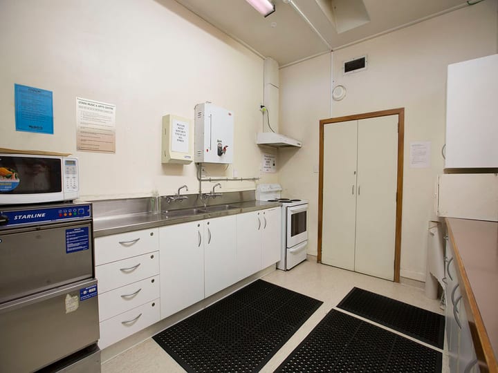Commercial kitchen with stainless bench, dishwasher, microwave, and oven