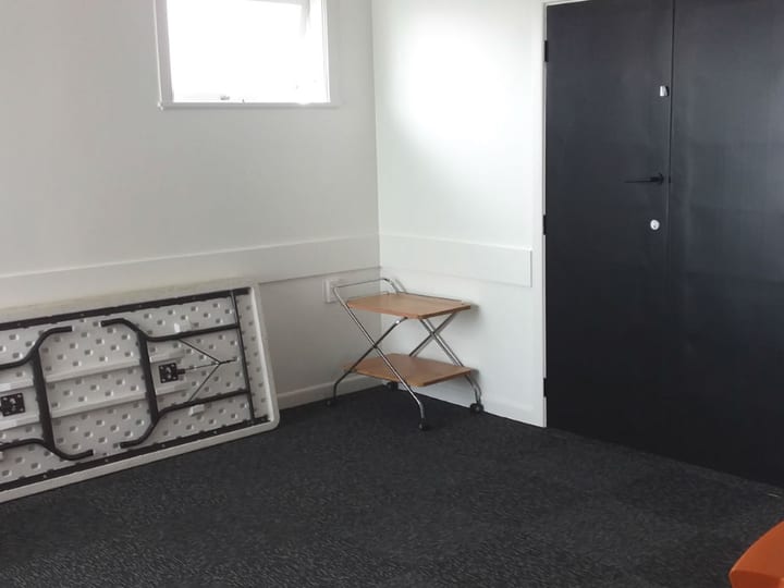 Plain room with folded table, small trolley and dark door