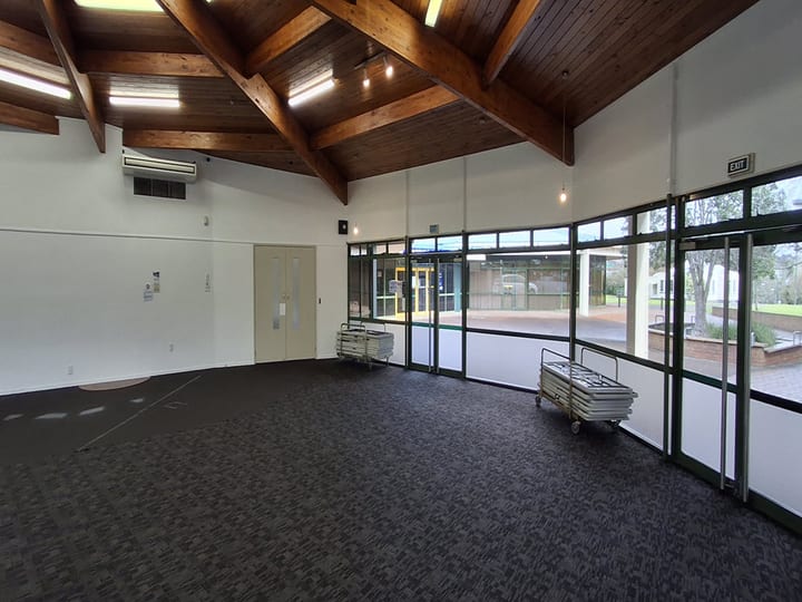 Hall with exposed timber roof beams, carpet floor and curved glazed wall
