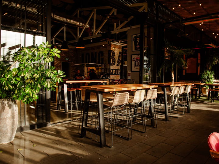 Large open bar and dining space with industrial ceiling and timber tables
