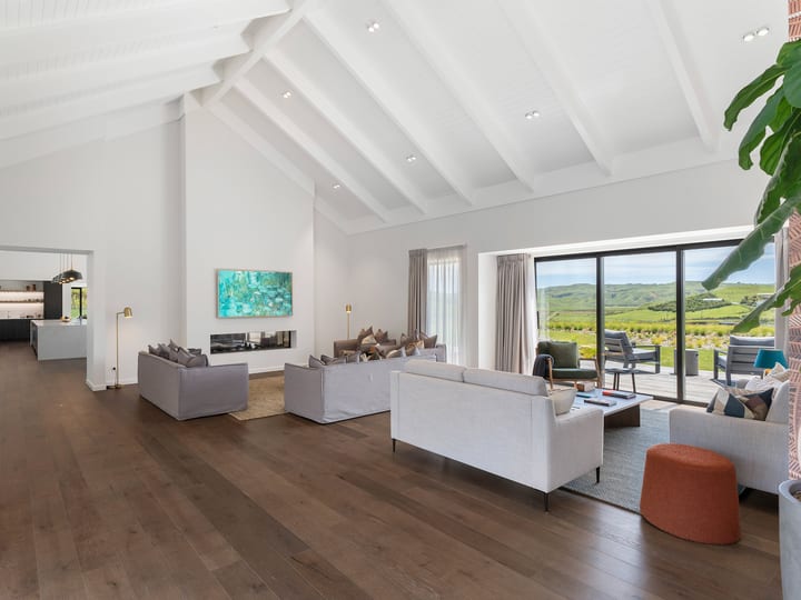 Open-plan living room with high vaulted ceiling, sofas and rural views through sliding doors