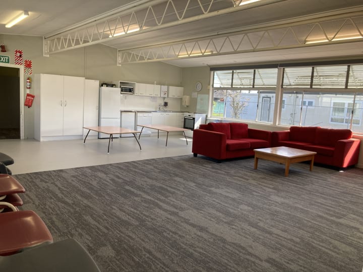 Community hall interior with kitchen bench, red sofas and carpet tiles
