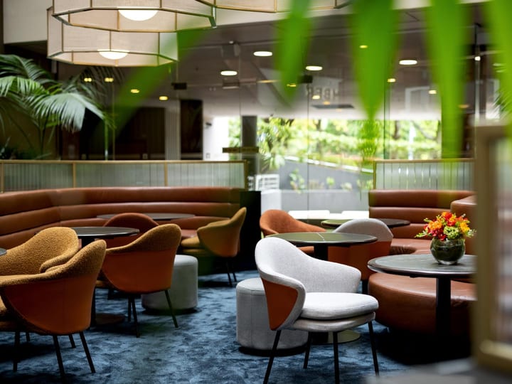 Lounge area with curved terracotta booth seating, round tables, and hanging pendant lights