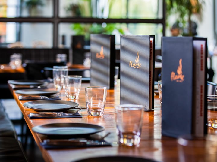 Restaurant dining setup with set table, menus, and large windows