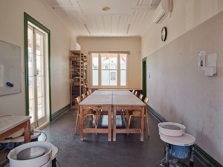 Studio room with work tables, pottery wheels, shelving, and tall windows