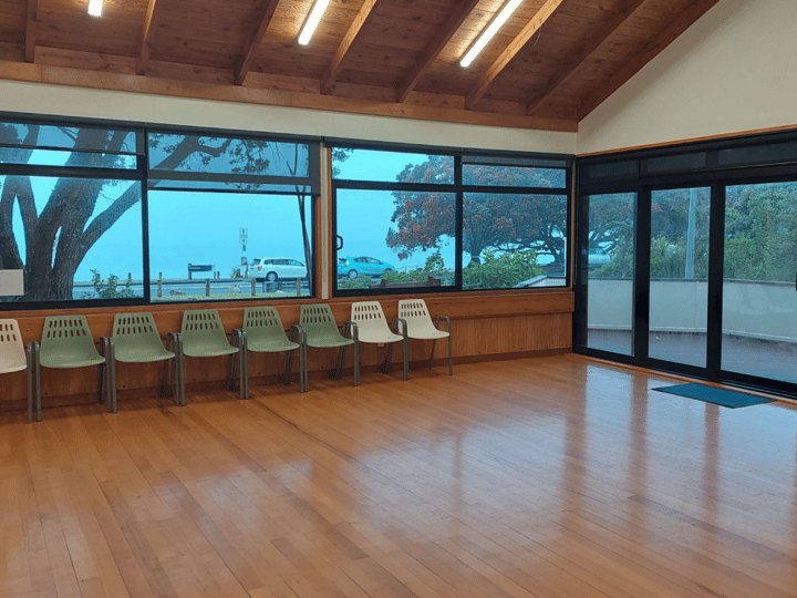 Foyer area with timber walls, polished floor, chairs along windows overlooking outside