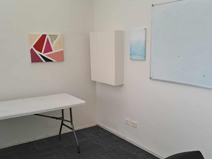 Small office-style room with folding table, whiteboard, and artwork on walls