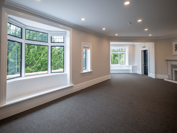 Open room with bay window, fireplace and carpet floor