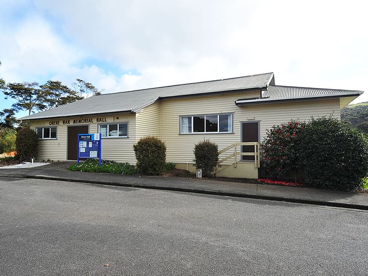 Front view of weatherboard hall with name signage and garden planting