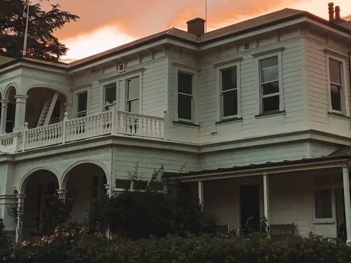 Heritage homestead exterior at dusk with warm sky and veranda detail