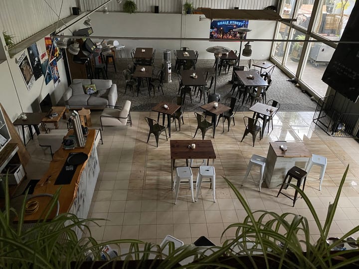 Industrial dining space viewed from above with metal chairs, wooden tables, and mezzanine