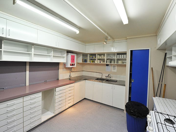 Utility kitchen with white cabinetry, bench counters, and open shelving with dishware