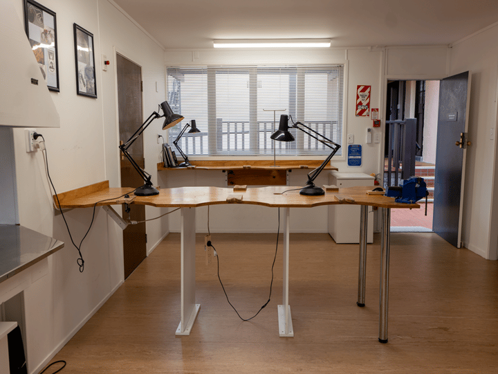 Workshop space with live-edge timber bench and task lamps, window behind