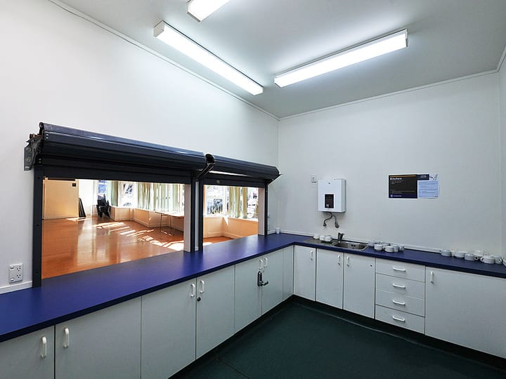 Hall interior showing raised stage with black curtains and polished timber floor