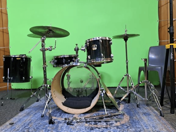 Drum kit set up in front of a green screen backdrop