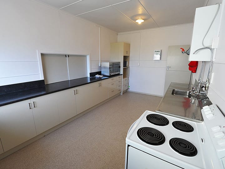 Hall kitchen with white cabinetry and electric stove