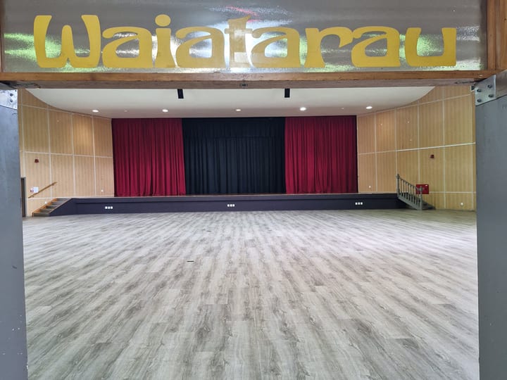 Hall interior with raised platform, red curtains and 'Waiafarau' signage above