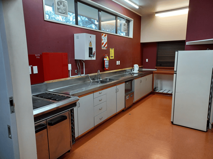Hall kitchen with stainless bench, commercial sink and appliances, red accent wall