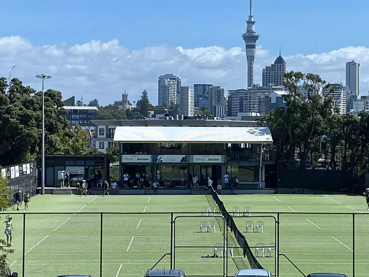 Tennis courts with pavilion building and Auckland city skyline behind