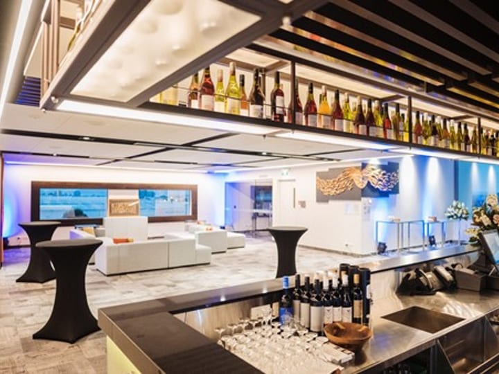 Hotel bar area with illuminated bottle display and open function lounge beyond