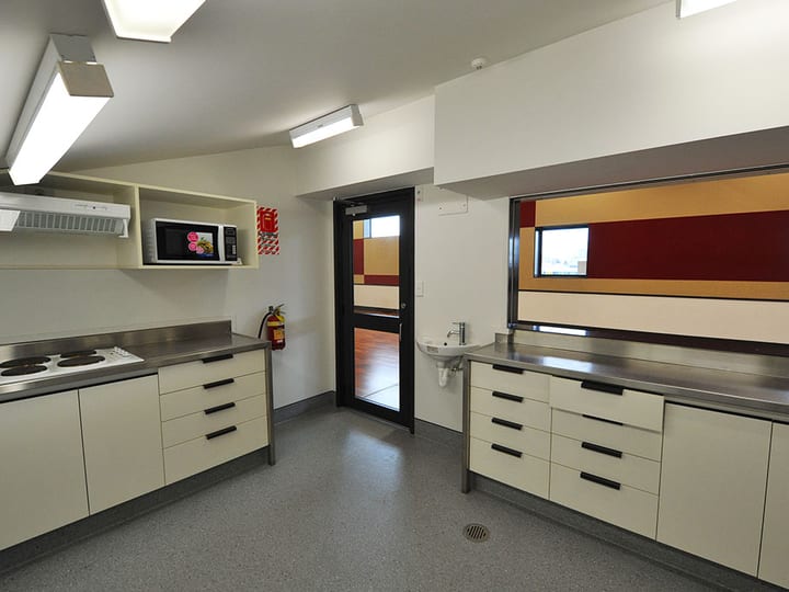 Catering kitchen with white cabinetry, stainless benches, electric hotplates, and microwave