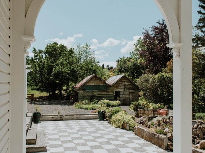 Covered veranda columns framing view of garden and outbuilding