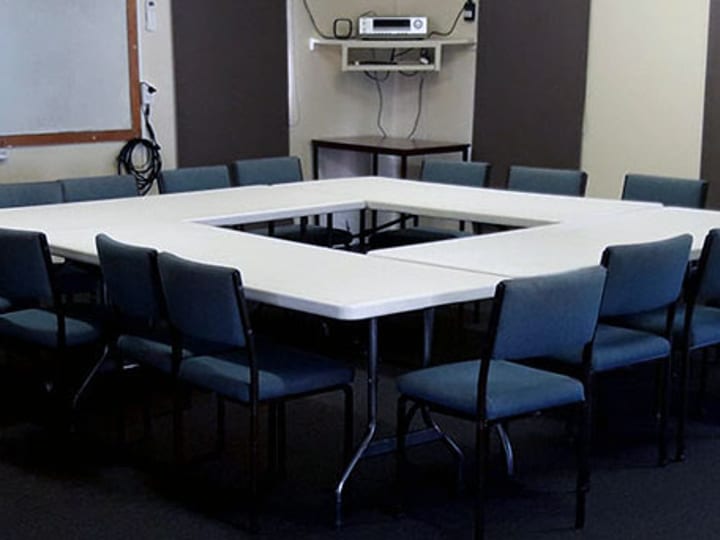 Meeting room with U-shaped table layout and whiteboard on wall