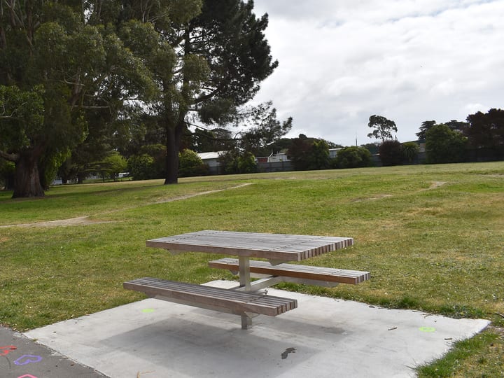 Park with picnic table, trees and painted pathway markings in foreground