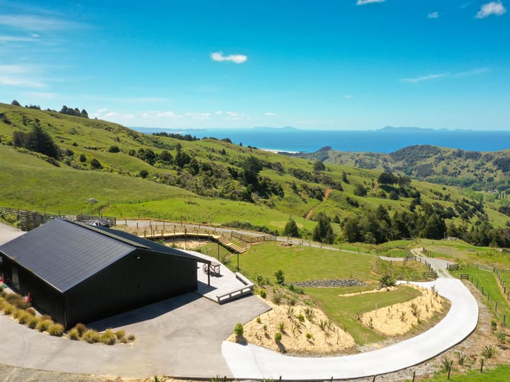 Aerial view of black barn venue beside a curved driveway with panoramic rural and coastal views