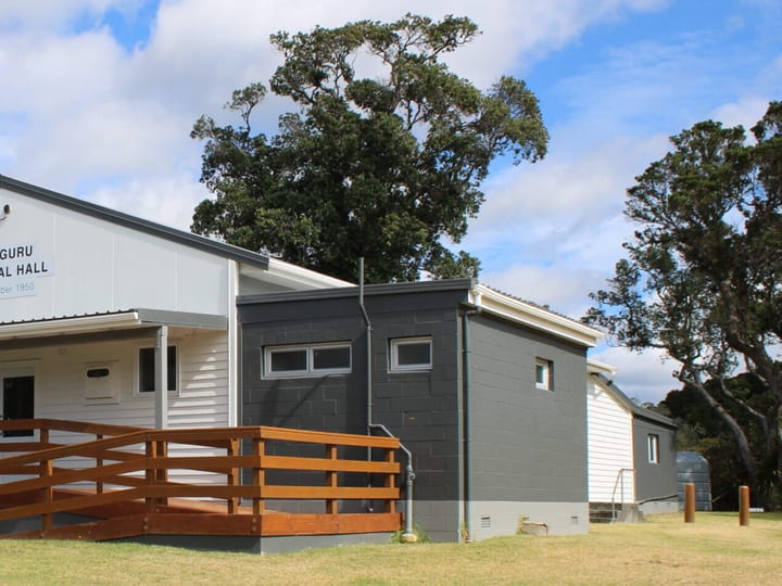Small white memorial hall with timber deck, ramp and dark addition at rear