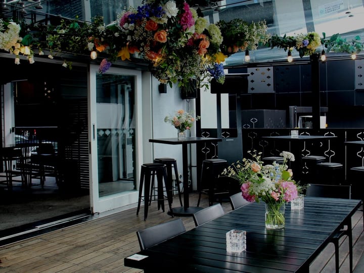 Outdoor terrace set with black tables and flower arrangements for an event