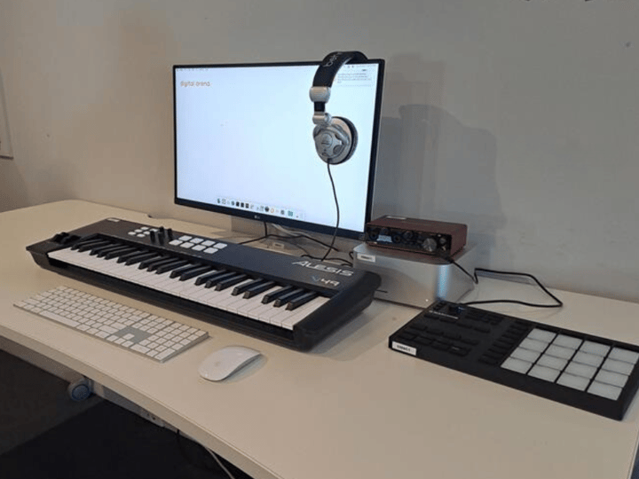 Music workstation with keyboard controller, monitor, and headphones
