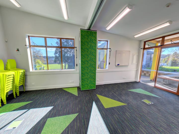 Activity room with patterned carpet, stacked yellow chairs, and movable partition