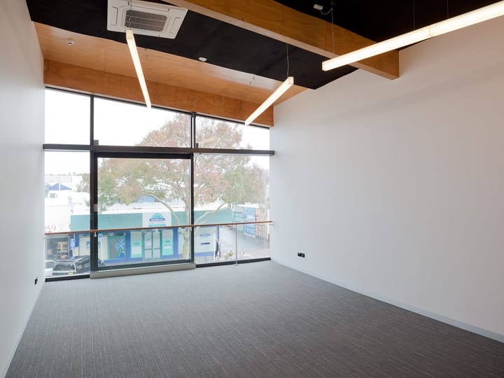 Empty room with carpet, wooden ceiling and large windows to street