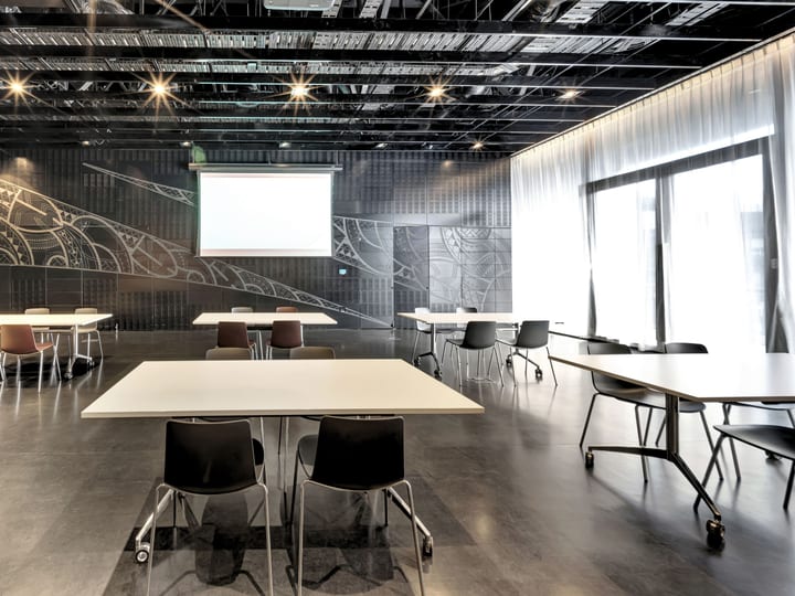 Meeting room with tables and chairs, dark feature wall with Maori-inspired mural