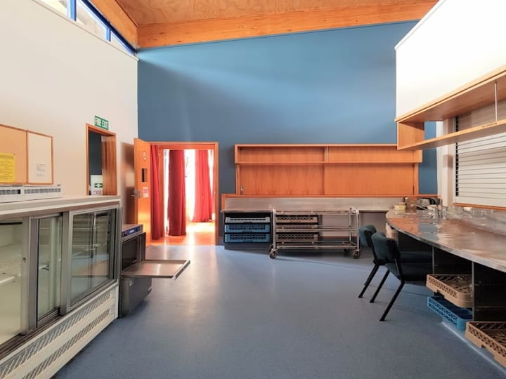 Catering prep room with refrigeration units, shelving, and pass-through to curtained hall