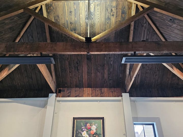 Interior ceiling with exposed timber trusses and artwork hanging on white wall