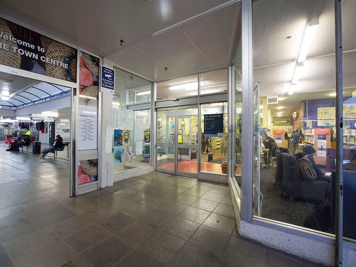 Library entrance viewed from covered walkway with signage visible inside