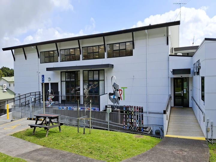 Same white two-storey building exterior from a slightly different angle showing accessible ramp and picnic table