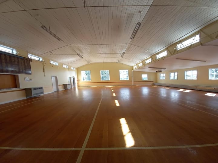 Large empty hall with polished timber floor and high clerestory windows