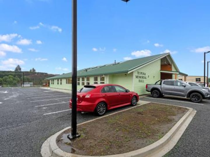 Three-quarter view of green memorial hall exterior with carpark