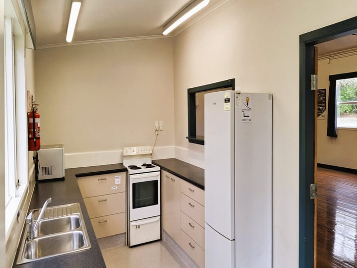 Hall kitchen with small stove, sink and fridge, door opening to the main hall