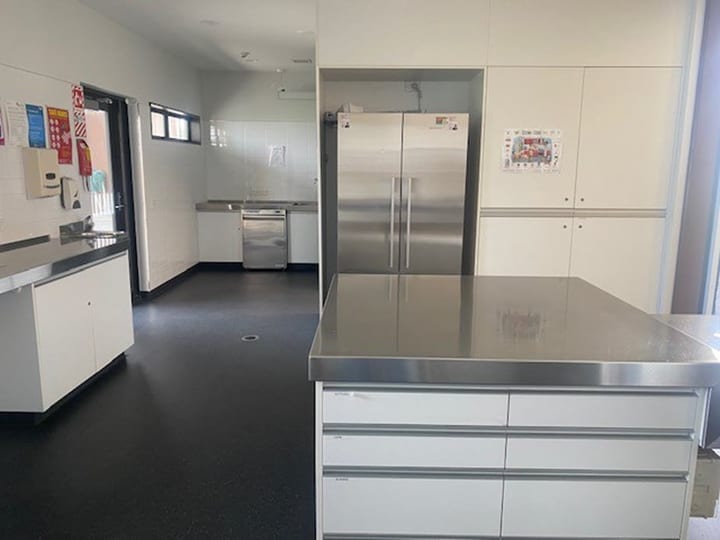 Functional kitchen facility with white cabinets, large refrigerator, and modern appliances.